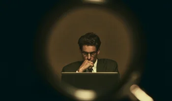 A student looking at a computer seen through a magnifying glass