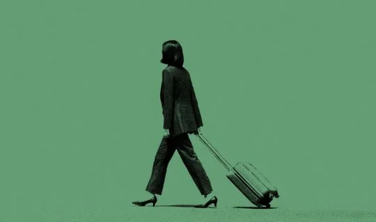 an Asian woman dragging a suitcase against a greenbackground